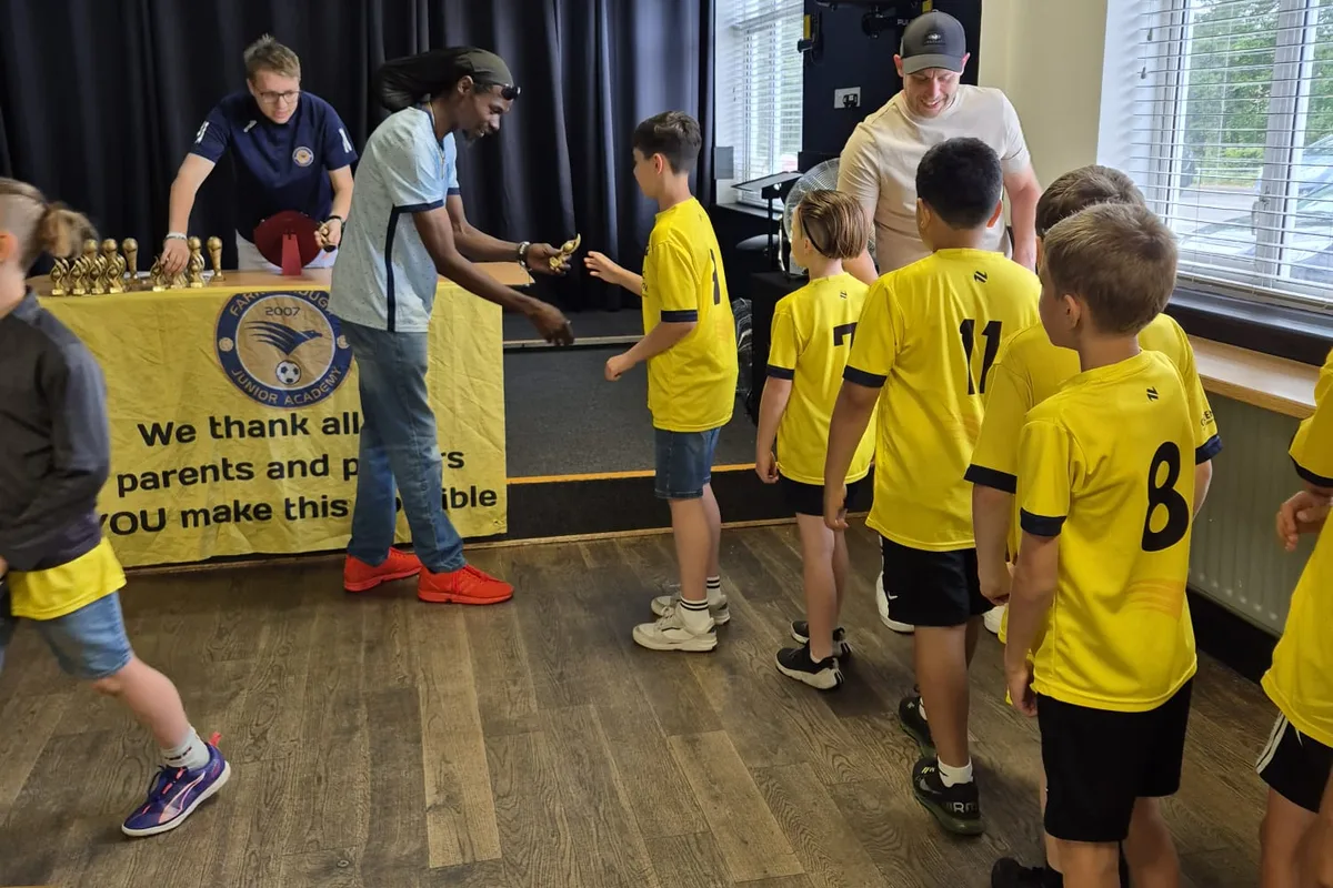 Collecting a trophy in front of the club banner thanking parents and players