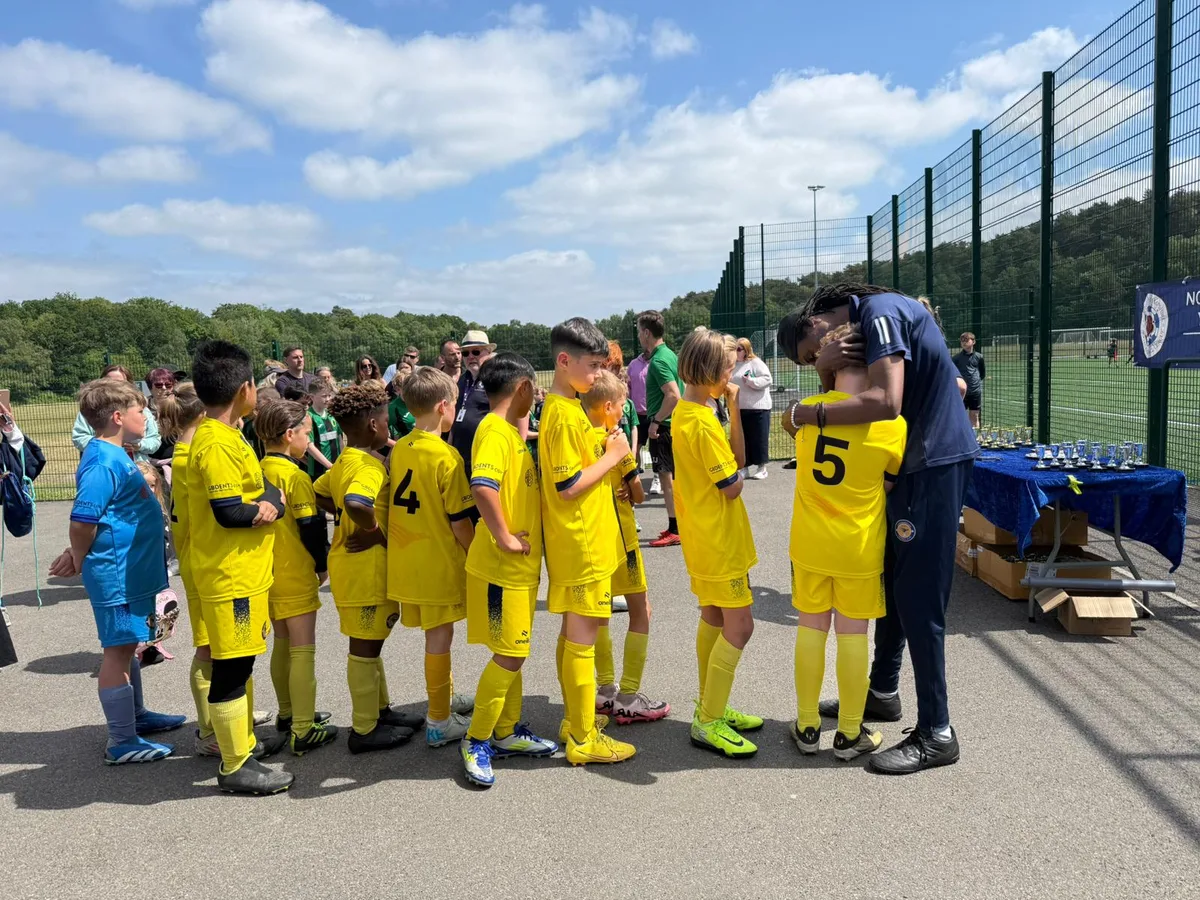 Lining up beside the trophy table at the cup finals, a coach with an arm round one of the players