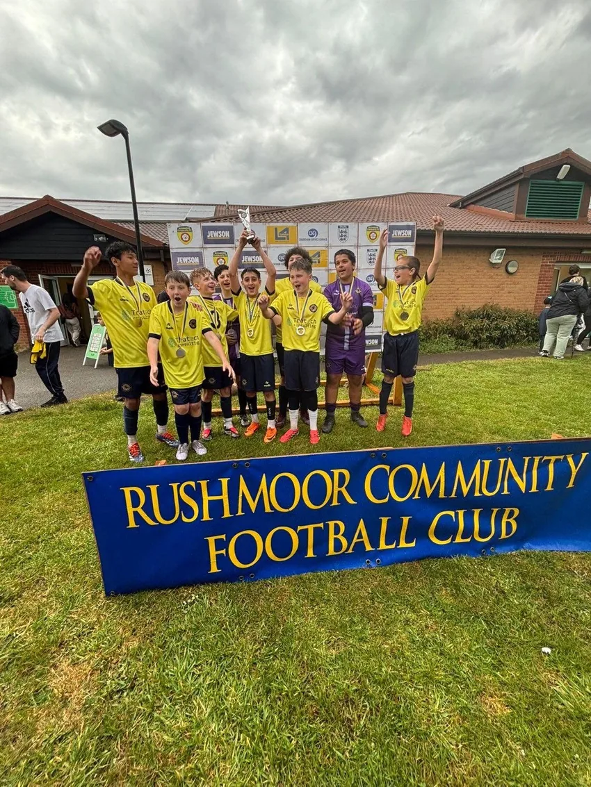 Players celebrating with arms aloft and a trophy after a tournament win.