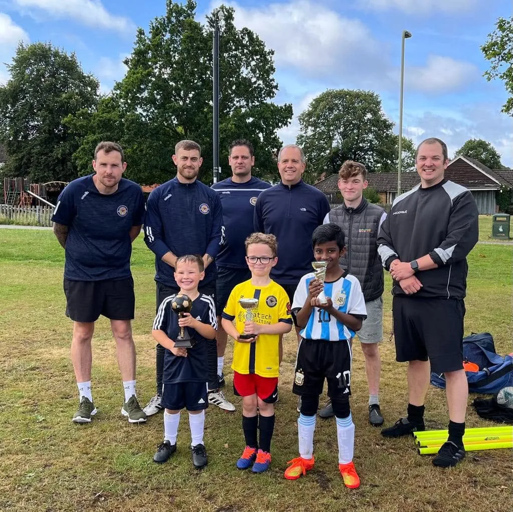 Coaches and young players holding their trophies on presentation day.