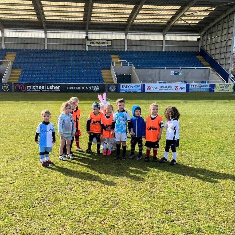 Mini-Kickers lined up on the pitch at a stadium.