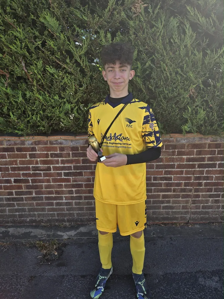 In front of a brick wall with a small gold trophy