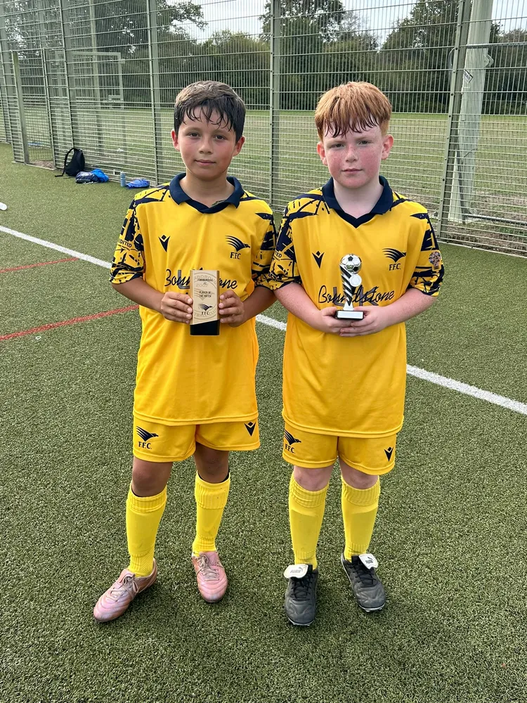 Side by side on the 3G pitch in the yellow home kit, each with a trophy