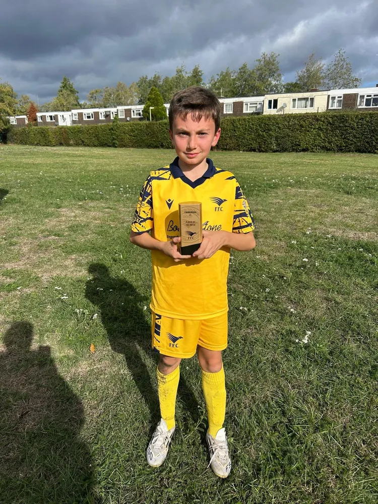 Serious face, white boots and the club trophy, with storm clouds gathering overhead