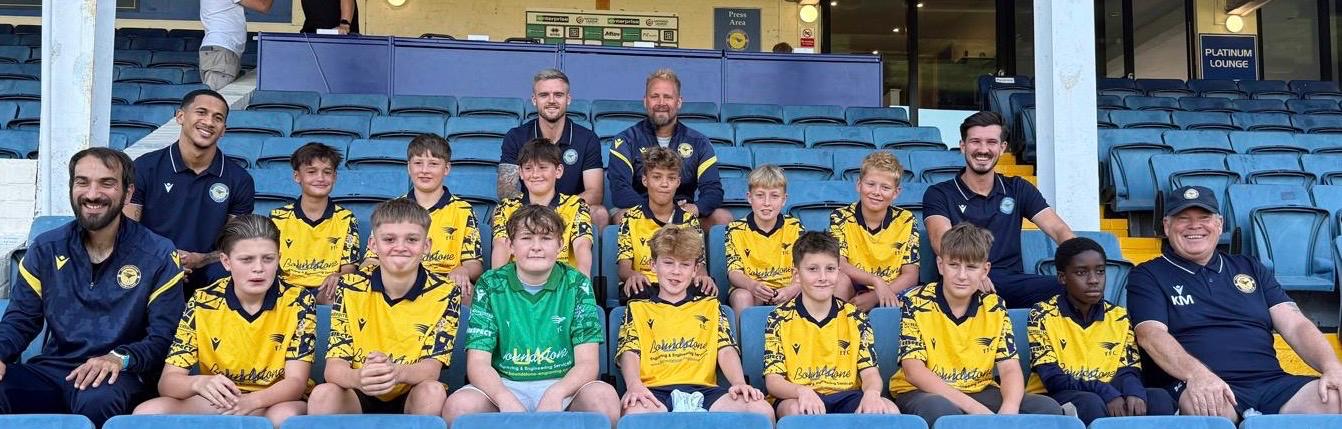 The Under 13 Yellows squad and their coaches sitting together in the stand at Farnborough FC